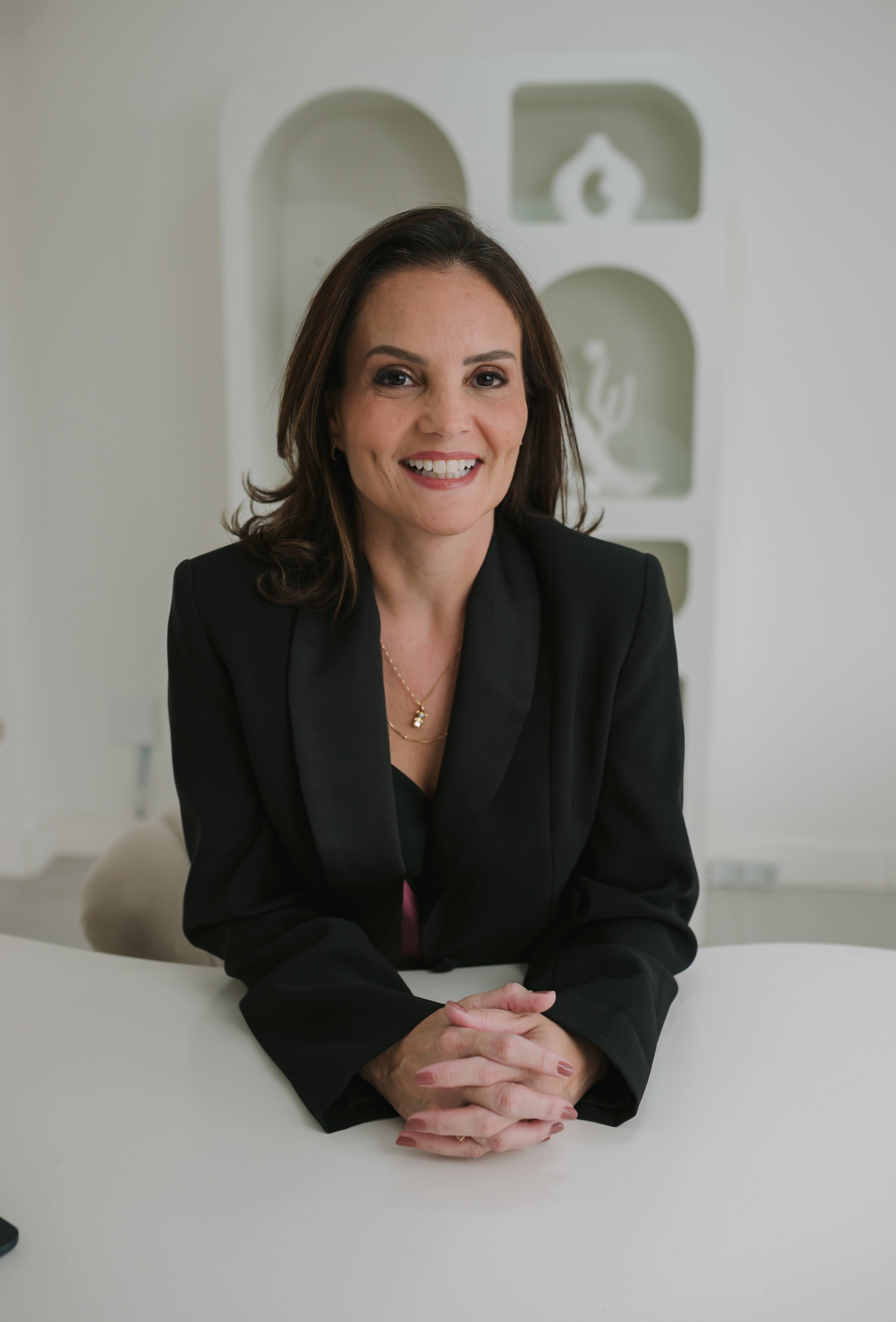 Dra. Maína Bonetti Villarinho sorrindo em ambiente profissional
